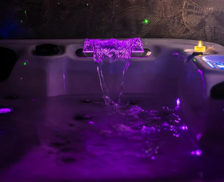 Jacuzzi intérieur avec sa cascade illuminée d'une violet éclatant.