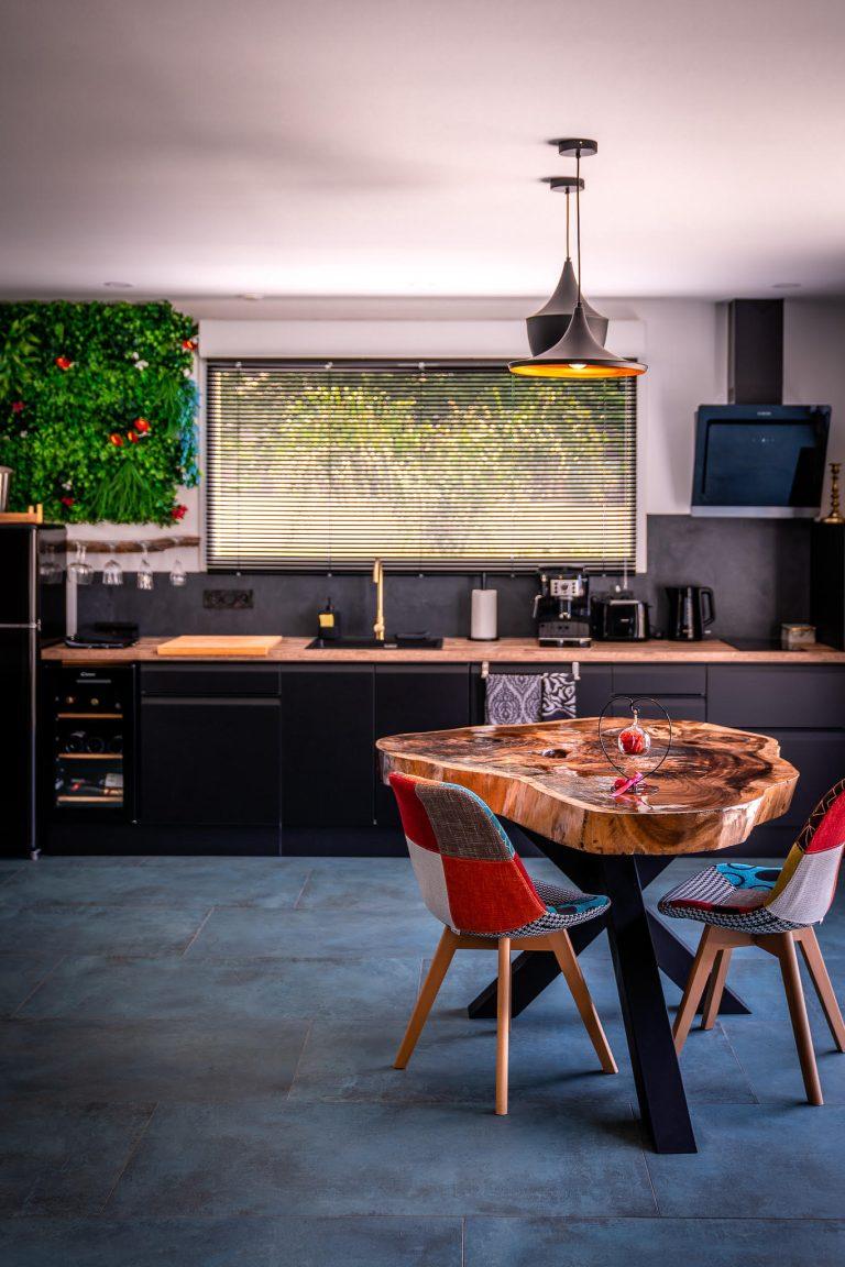 Cuisine équiper noir mat avec mur végetal et table en bois massif sur un magnifique pied en métal.